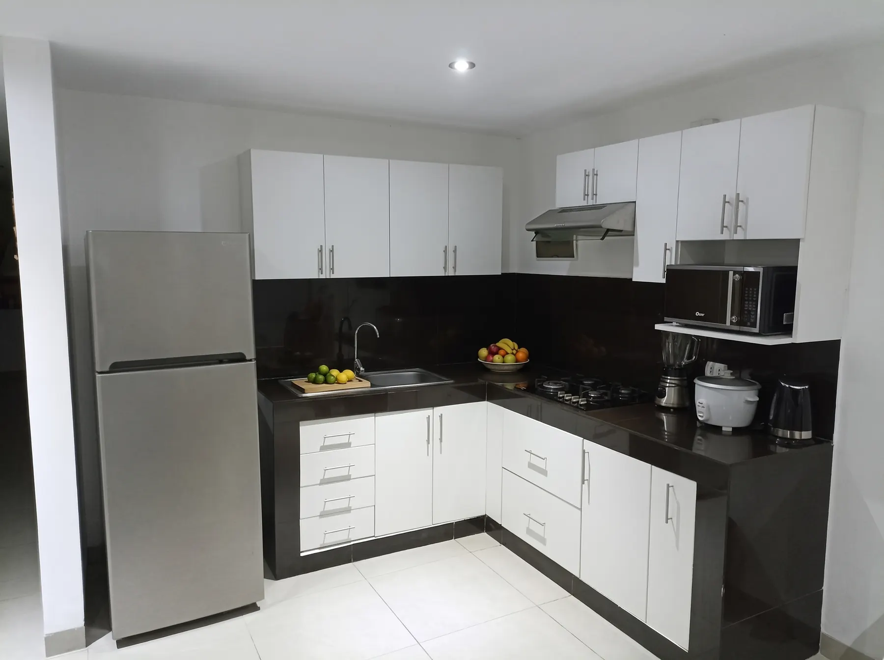 Cocina en L equipada con refrigeradora, microondas, licuadora, olla arrocera y hervidor
