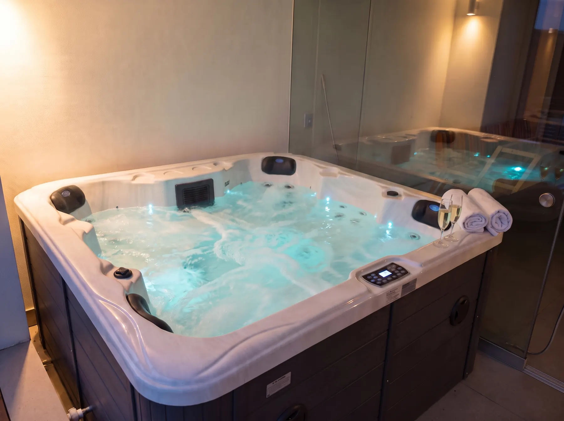 Jacuzzi con hidromasaje de noche con luz turquesa, toallas y copas